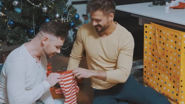 Милая гей-пара проверяет рождественские чулки на наличие подарков — стоковое видео