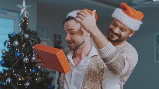 Рождественский обмен подарками в гомосексуальной семье. Красивая гей-пара празднует Рождество — стоковое видео