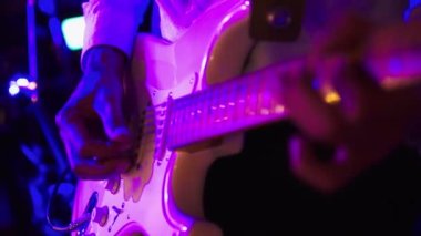 Erkek gitarist bir rock konserinde ya da kulüpte elektro gitar çalıyor. Mavi kırmızı ışık