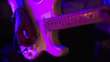 Erkek gitarist bir rock konserinde ya da kulüpte elektro gitar çalıyor. Mavi kırmızı ışık
