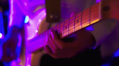 Erkek gitarist bir rock konserinde ya da kulüpte elektro gitar çalıyor. Mavi kırmızı ışık
