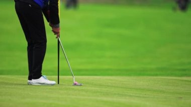 Adam sallanıyor ve golf topuna vuruyor. Çukura yuvarlanıyor