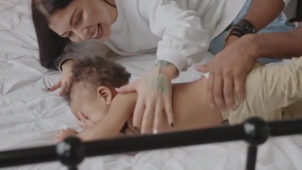 Mutlu melez aile yatakta bebekle oynuyor. — Stok video