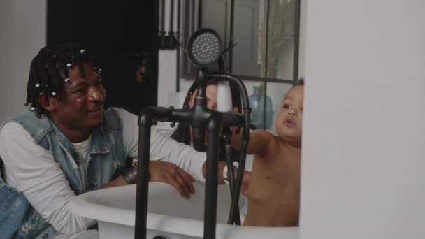 Baby bath. Mixed race baby playing in a bath with caucasian mother and african american father — Vídeo de Stock