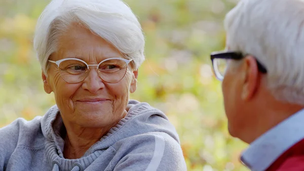 Ancianos abuelos de pelo gris sonriéndose y hablando mientras pasan tiempo al aire libre. —  Fotos de Stock