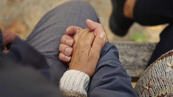Kafkasyalı yaşlı çift bir bankta otururken yaşlı, buruşuk ellerini bir arada tutuyorlar.. — Stok fotoğraf