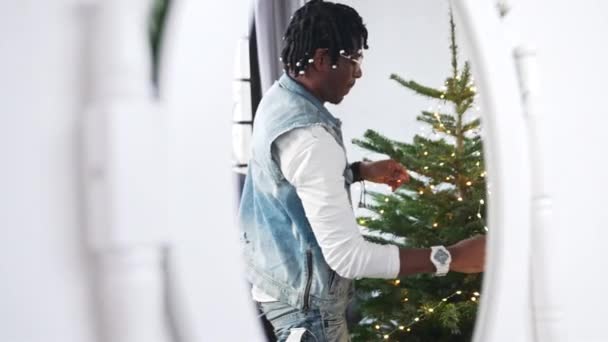 Specchio riflesso dell'uomo afro-americano che veste un albero di Natale. — Video Stock