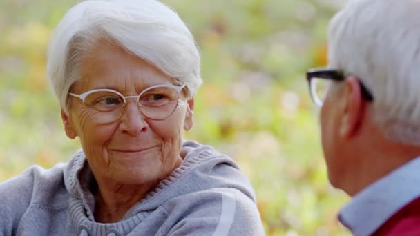 Ældre gråhårede pensionist dame nyder sin pensionering og tilbringe tid i en park med sine voksne venner. Udendørs close up skud. – Stock-video