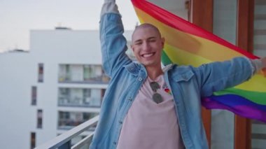 Gökkuşağı gurur bayrağı sallayan ve Gurur Ayı 'nı kutlayan görkemli, mutlu, kel, beyaz, eşcinsel bir adam..