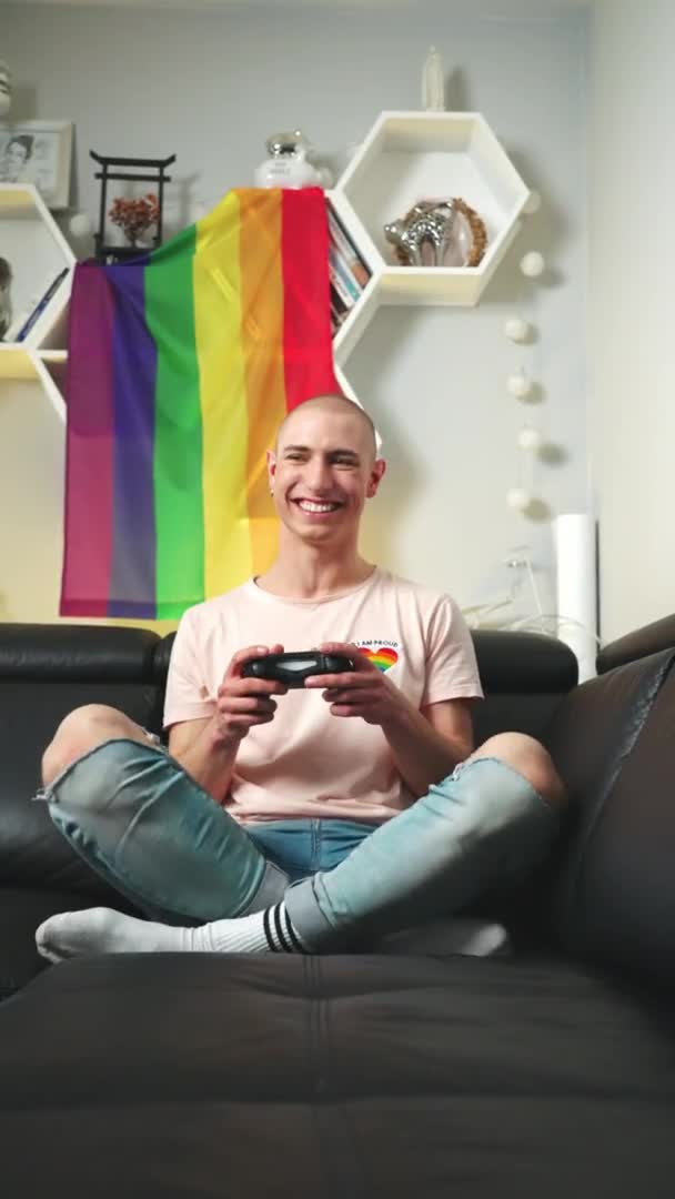 Vertical shot of content and grinning queer non-binary gamer playing with gamepad and enjoying free time. — Stock video