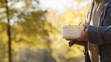Evsizlere, fakirlere, muhtaç insanlara yardım eden gönüllülerin hazırladığı besleyici yiyeceklerle dolu plastik bir kaseyi elinde tutan kişi..
