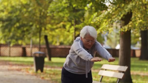 Eine ältere kaukasische Frau streckt sich im öffentlichen Park. Gesunder und aktiver Lebensstil ab 60. — Stockvideo
