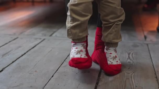 Батько вчиться малюку ходити. Малі ноги, що стоять на дорослих ногах. Різдвяні шкарпетки . — стокове відео