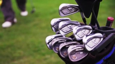 Siyah çantalı gümüş golf sopaları arka planda. Detaylı çekim.