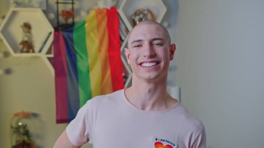 Beyaz tenli kel, eşcinsel, gökkuşağı gurur bayrağının önünde poz veriyor..