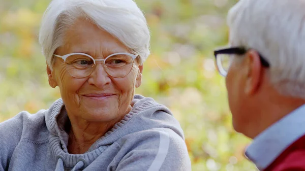 Mujer jubilada de 70 años sonriendo, y hablando con su marido. Al aire libre tiro de cerca. —  Fotos de Stock