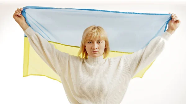 Ernsthafte Frau hüllt sich in ukrainische Flagge. Weißer Hintergrund — Stockfoto