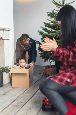 Sevimli melez çocuk bir kutuda otururken ve babası tarafından itilirken eğleniyor..