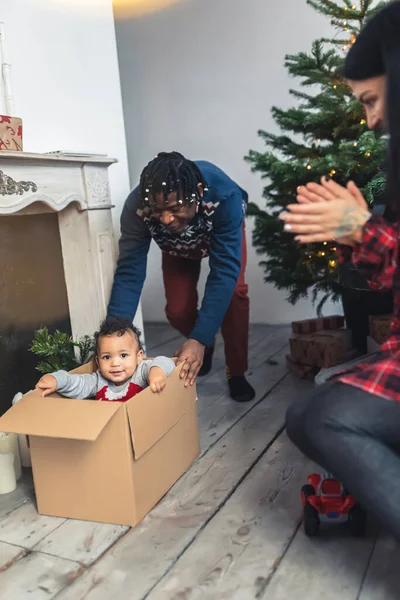 Εναλλακτικό αστείο παιχνίδι, Αφρο-Αμερικανός γονέας πιέζει το παιδί του σε ένα κουτί. Κάθετη εσωτερική λήψη. — Φωτογραφία Αρχείου