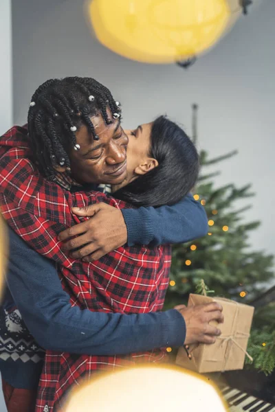 Όμορφη αγκαλιά μεταξύ διαφυλετικών συζύγων κατά τη διάρκεια της παραμονής των Χριστουγέννων. — Φωτογραφία Αρχείου
