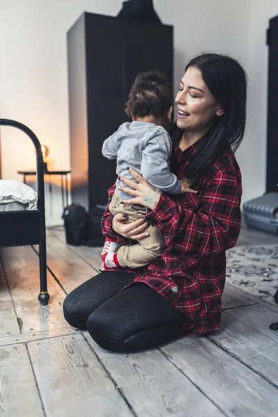 Genç Avrupalı annenin melez bebeğini kucağına alıp onu yatıştırdığı dikey bir fotoğraf.. — Stok fotoğraf