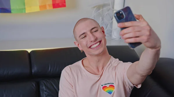 Queer non-binary bald influencer takes a selfie with rainbow pride flag. — Stock Photo, Image