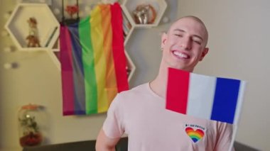 Fransa 'da yaşayan, Fransız bayrağını sallayan ve kameraya baş parmağını gösteren tuhaf, beyaz, mutlu eşcinsel bir adam..