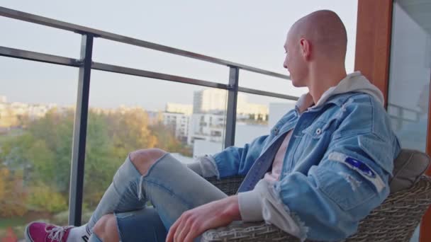 Vit skallig homosexuell man som kopplar av på balkongen, njuter av frisk luft och bra väder. — Stockvideo