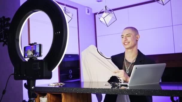 Caucasian queer lgbt person does fashion haul, shows brand new white t-shirt to the camera, and talks about clothes — Stock Video