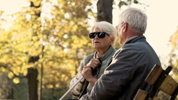Старший кавказский мужчина проводит время со своей слепой женой-инвалидом в парке, оглядываясь назад. — стоковое видео