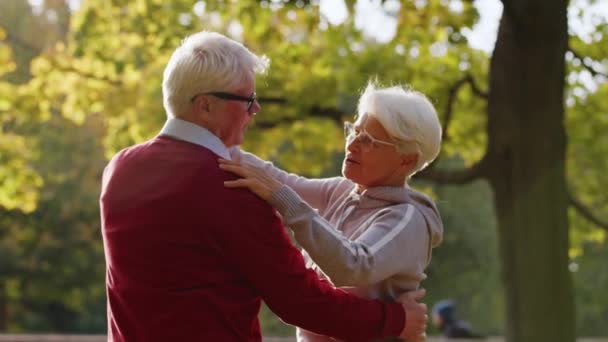 Старшая кавказская пара танцует в парке счастливой пенсионной концепции случайный наряд — стоковое видео