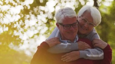 Yaşlı beyaz kadın kocasına sırtından sarılıyor gülümsüyor ve başını sallıyor. Seçici odak noktası fotokopi alanı 
