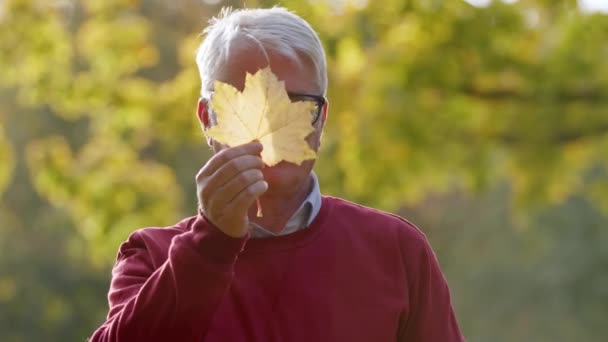 Bărbat caucazian de vârstă mijlocie care arată o frunză camerei, arătându-și mai târziu portretul selectiv al feței — Videoclip de stoc