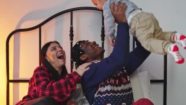 幸せな愛情のある若い黒のお父さんベッドの中で愛らしい混合レースの赤ちゃんの男の子を持ち上げる。家族の概念を愛する. — ストック動画