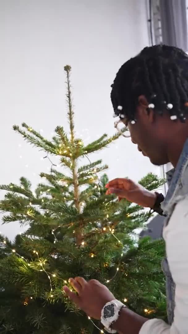 Αφροαμερικανός μεσήλικας που στολίζει το Χριστουγεννιάτικο Δέντρο. Κάθετη βολή. — Αρχείο Βίντεο