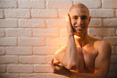 Üstsüz, gururlu, beyaz, kel, eşcinsel adam. Vogue yapıyor, gülümsüyor ve güzel, doğal güneş ışığıyla poz veriyor ve kameraya bakıyor.