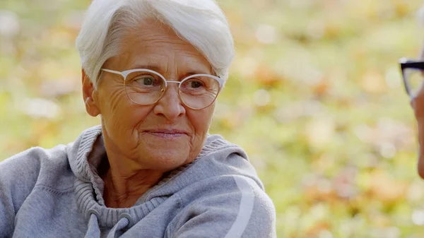Retrato de anciana mujer caucásica pelo gris y gafas mirando a su marido en el parque personas mayores apoyo concepto enfoque selectivo espacio de copia —  Fotos de Stock