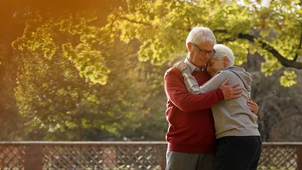 Ältere kaukasische Paare umarmen sich im Park Wohlbefinden Senioren unterstützen Konzept selektiven Fokus kopieren Raum Medium shot — Stockfoto