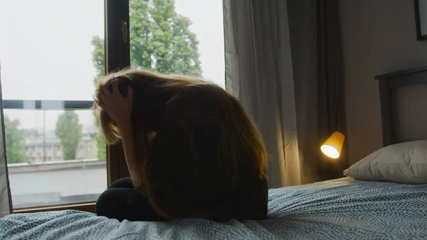 विनाशकारी काकेशियन महिला अपने लंबे बालों को छू रही है, घर पर बिस्तर पर बैठी है, समस्याओं के बारे में सोच रही है . — स्टॉक फ़ोटो, इमेज