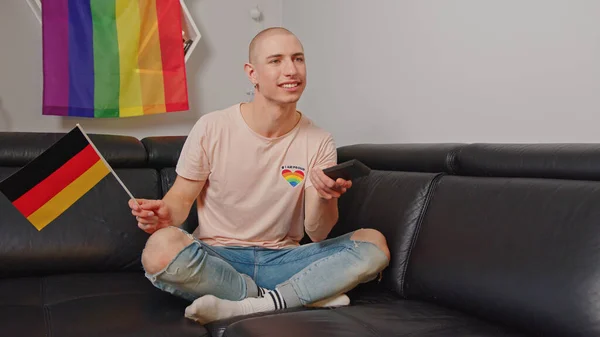 Almanya 'da yaşayan ve koltukta oturup seçimleri izlerken Alman bayrağı sallayan gururlu Avrupalı eşcinsel.. — Stok fotoğraf
