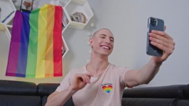 Sırtında gökkuşağı gurur bayrağıyla sosyal medyadaki takipçilerine eşcinsel, kel olmayan etkileyicisi el sallıyor..