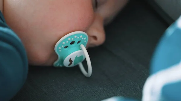 Bedtime concept. Close up shot of a little toddler sucking on a turquoise dummy. — Stock Photo, Image