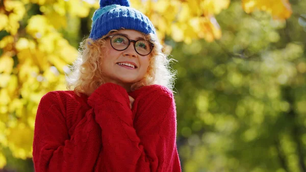 Ich liebe den Herbst. Positive bunte Bild eines jungen blonden lockigen kaukasischen Mädchen mit Wintermütze und Brille lächelnd und verträumt aussehend. — Stockfoto