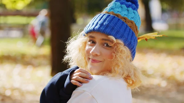 Breng uw vrije tijd buiten door. Portret van een mooi duizendjarig blank meisje kijkend naar de camera, met kleurrijke gebreide muts op. — Stockfoto