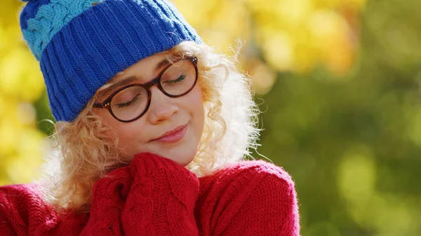 Mavi şapkalı ve gözlüklü güzel, kıvırcık saçlı kadın, ellerini yüzüne yakın tutuyor, arka plan fotokopi alanı 