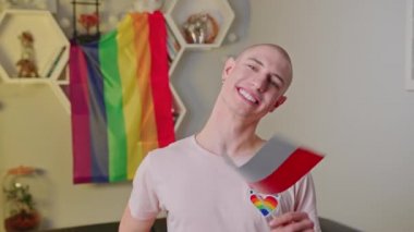 Happy Polish gay man waving his country flag to the camera. LGBTQ community living in Poland. Rainbow flag in the background. High quality 4k footage