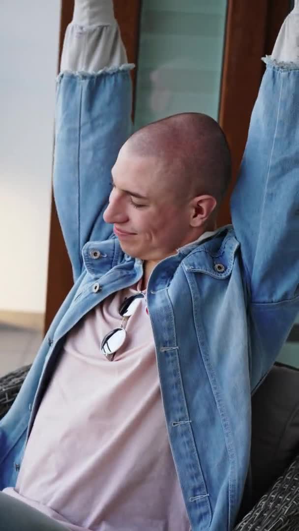 Pionowe Ujęcie Odmieńczej Niebinarnej Łysej Osoby Kurtce Jeansowej Siedzącej Balkonie — Wideo stockowe