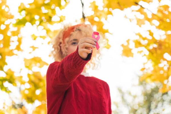 Hübsche junge blonde Frau zeigt rosa Schleife in die Kamera, Konzept Rosa Oktober mittlere Nahaufnahme — Stockfoto