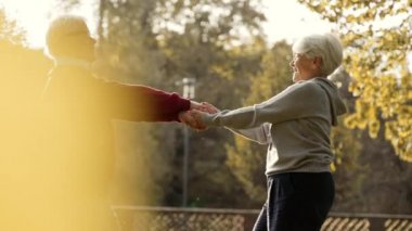 Orta yaşlı beyaz evli insanlar parkta dans eder, el ele tutuşur ve orta derecede gülümserler. Yüksek kalite 4k görüntü