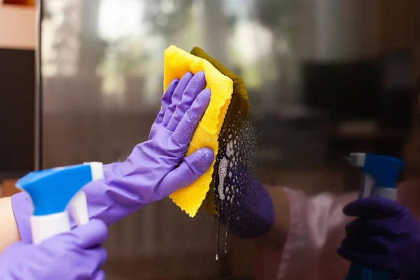 Hand in a purple glove wipes the TV screen with a rag — Stock Photo, Image